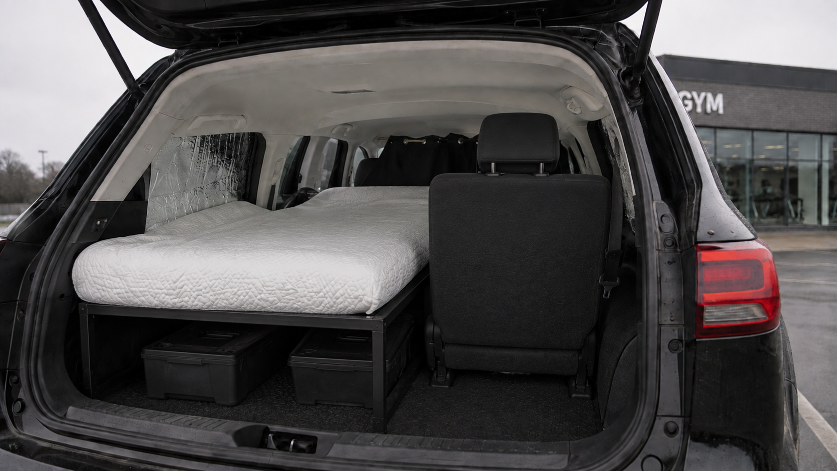 The boot view: upright seat on the right, mattress on a raised frame with storage on the left